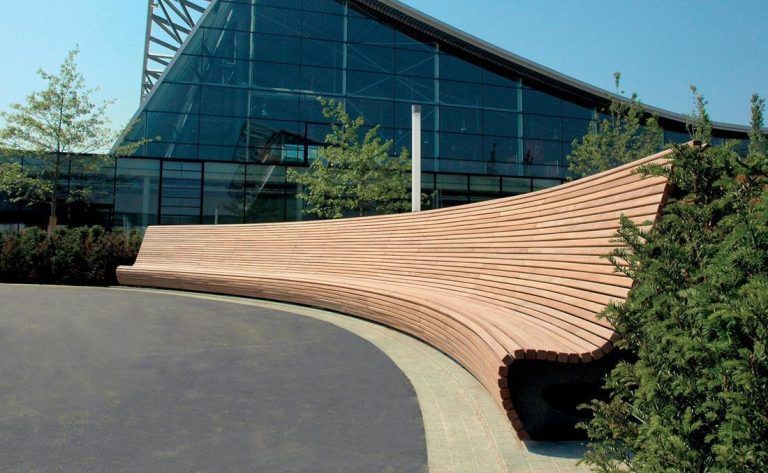 Banco urbano curvo exterior de madera.